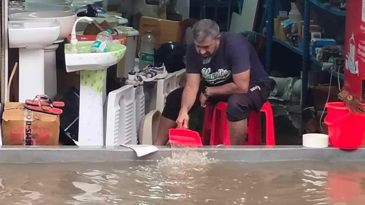 A shopkeeper is draining water by himself to clean the water.